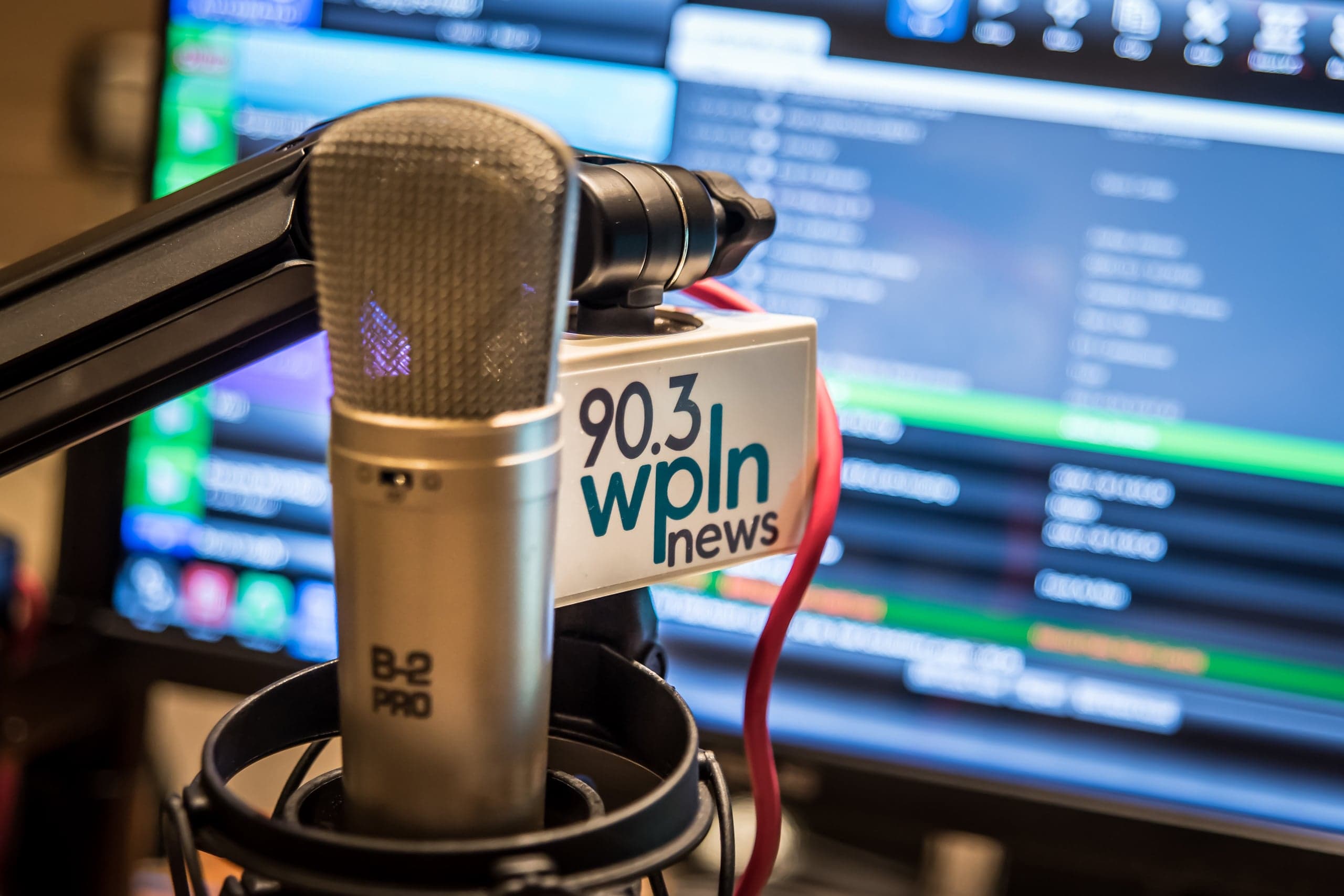Two close-up views of microphones in radio studios, one labeled “90.3 WPLN News,” the other “WNXP 91.1 FM,” showing broadcast equipment and blurred backgrounds.